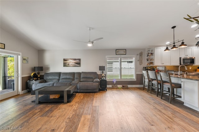 living room featuring a wealth of natural light, ceiling fan, vaulted ceiling, and light hardwood / wood-style floors