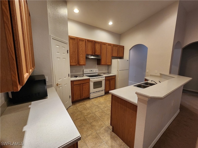 kitchen with kitchen peninsula, white appliances, sink, and a kitchen bar