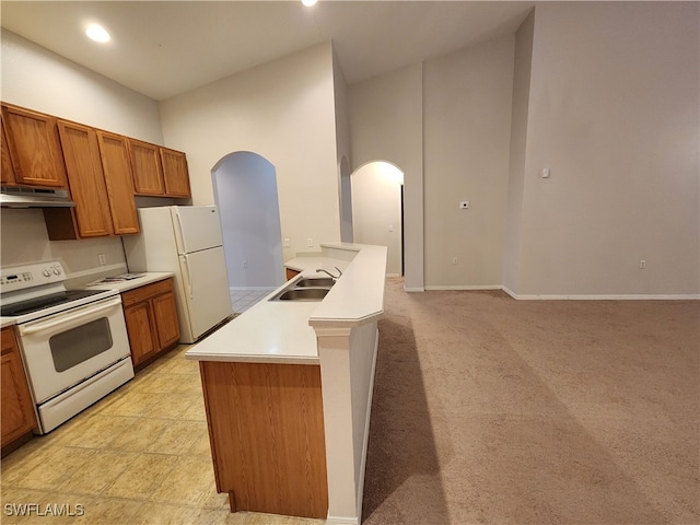 kitchen featuring a center island with sink, white appliances, light carpet, and sink