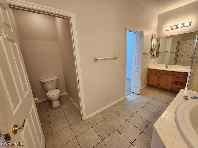 bathroom with vanity, tile patterned flooring, toilet, and a relaxing tiled tub