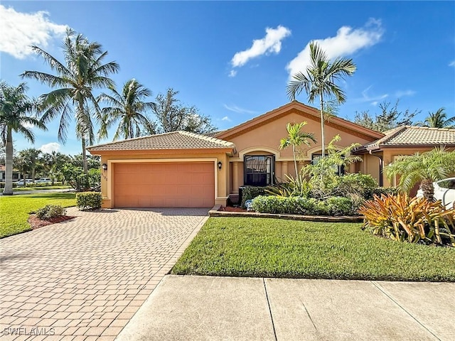 mediterranean / spanish house featuring a front lawn, decorative driveway, an attached garage, and stucco siding