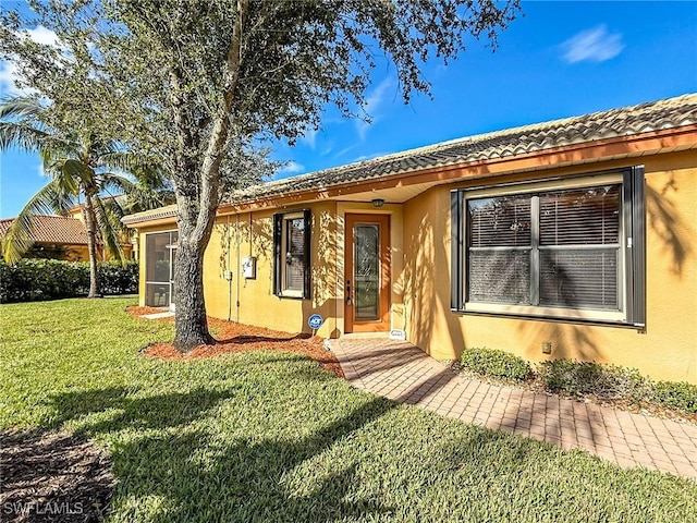 view of front of property featuring a tiled roof, a front yard, and stucco siding