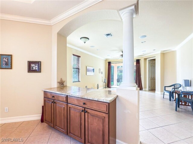 kitchen featuring visible vents, light stone counters, crown molding, ornate columns, and light tile patterned flooring