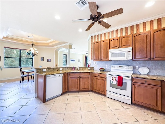 kitchen featuring white appliances, ornamental molding, brown cabinetry, a raised ceiling, and pendant lighting