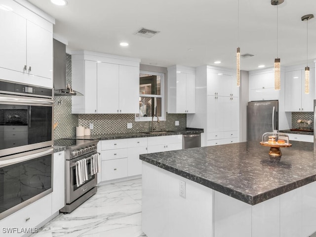 kitchen with wall chimney range hood, white cabinets, and stainless steel appliances