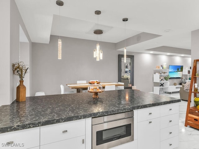 kitchen with white cabinetry, hanging light fixtures, and dark stone countertops