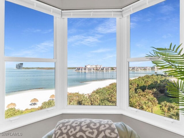 sunroom / solarium featuring a wealth of natural light, a beach view, and a water view