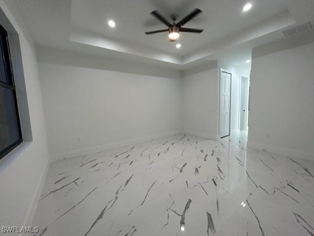 unfurnished room featuring a raised ceiling and ceiling fan