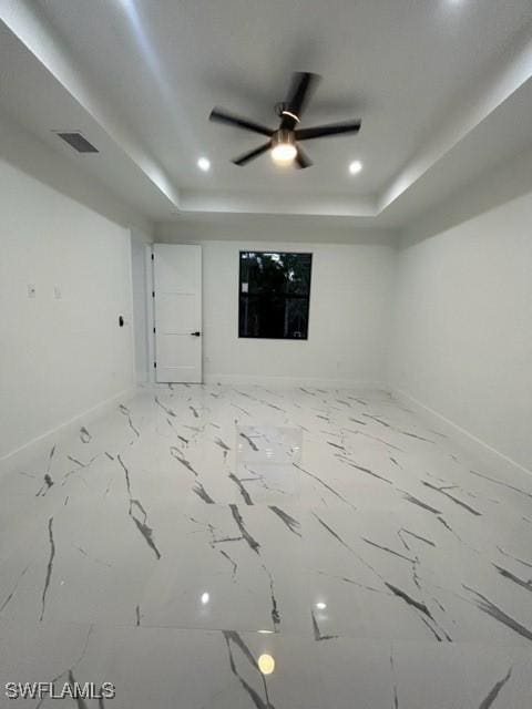 empty room featuring ceiling fan and a tray ceiling