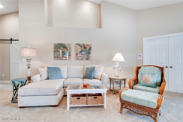 carpeted living room featuring a towering ceiling and a barn door