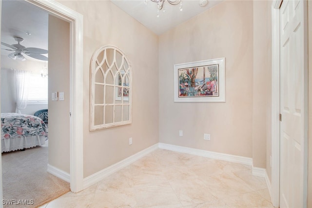 spare room with ceiling fan with notable chandelier