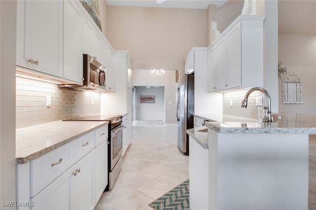 kitchen with light tile patterned floors, light stone counters, white cabinetry, and appliances with stainless steel finishes