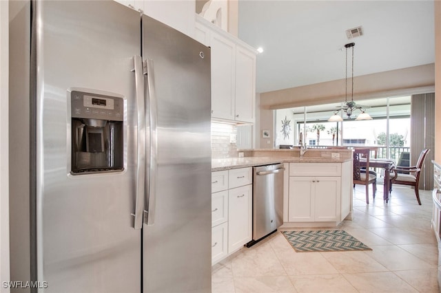 kitchen featuring light stone countertops, stainless steel appliances, decorative light fixtures, decorative backsplash, and white cabinets