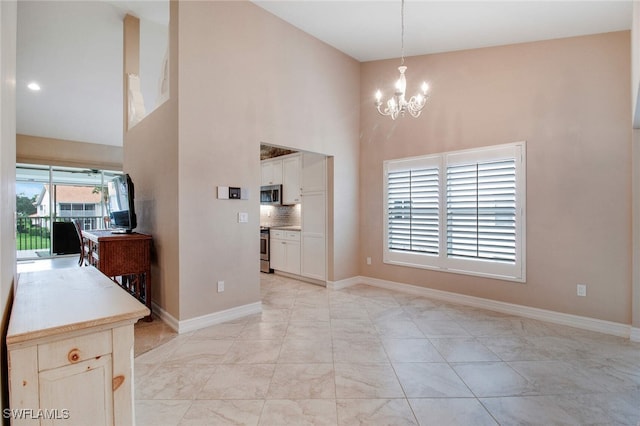 unfurnished dining area featuring a high ceiling and an inviting chandelier