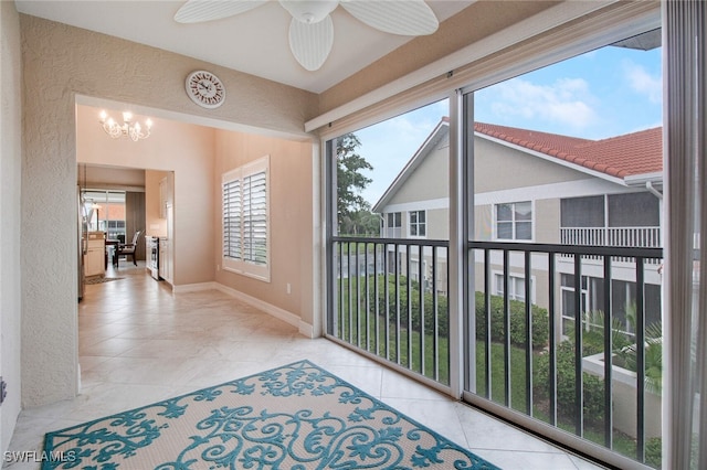 sunroom with ceiling fan with notable chandelier