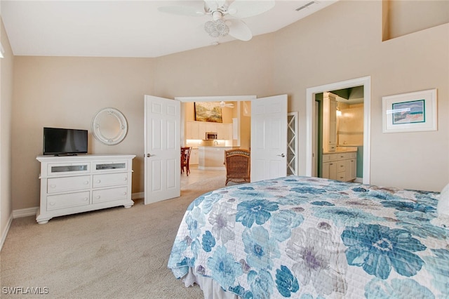 bedroom featuring ceiling fan, light carpet, high vaulted ceiling, and ensuite bath