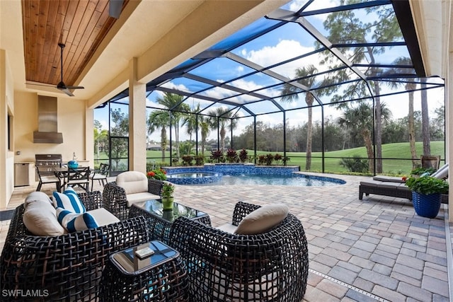 view of swimming pool featuring pool water feature, an in ground hot tub, exterior kitchen, a patio, and glass enclosure