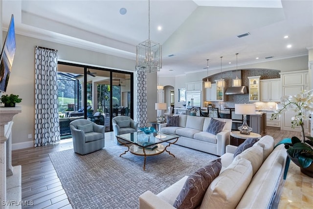 living room with ceiling fan with notable chandelier, a fireplace, lofted ceiling, and crown molding