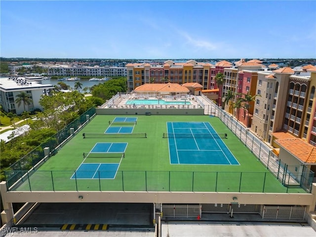 view of tennis court featuring a water view and a community pool