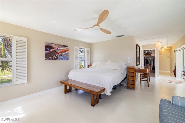 bedroom with concrete flooring, ceiling fan, a closet, and a spacious closet