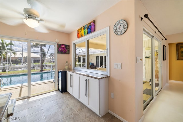 kitchen with white cabinets, dark stone counters, ceiling fan, and light tile patterned floors