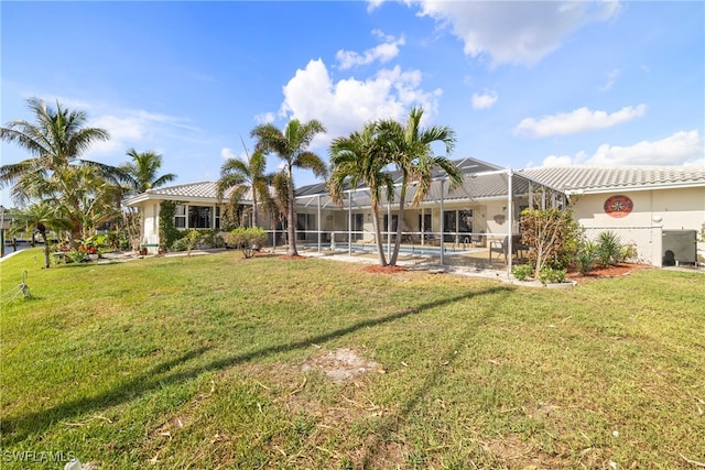 rear view of house with a swimming pool, glass enclosure, a lawn, and a patio