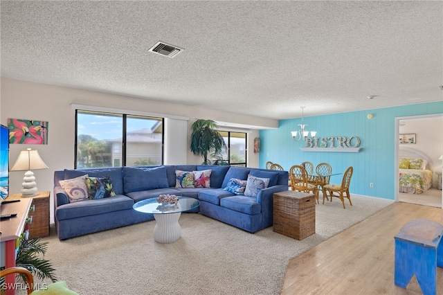 living room featuring wood-type flooring, a textured ceiling, and a notable chandelier