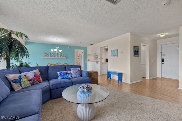 living room featuring a textured ceiling, a notable chandelier, and light hardwood / wood-style floors