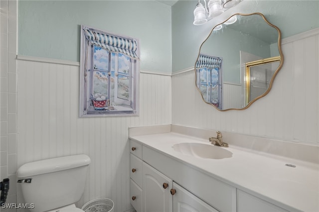 bathroom featuring a shower with door, vanity, and toilet