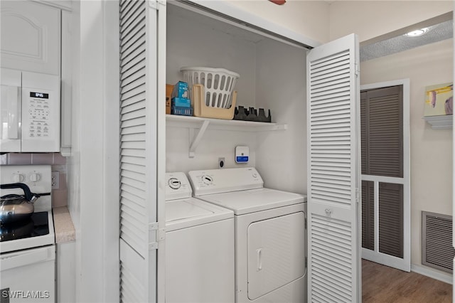 laundry area featuring wood-type flooring, a textured ceiling, and washing machine and dryer