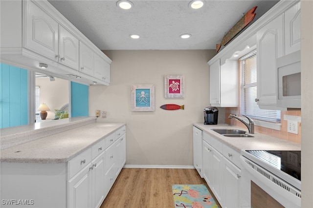 kitchen with white cabinetry, sink, a textured ceiling, white appliances, and light wood-type flooring