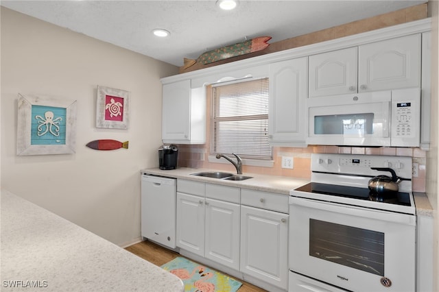 kitchen with white cabinets, light hardwood / wood-style floors, sink, and white appliances