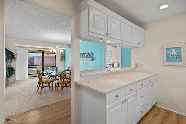 kitchen featuring white cabinetry, light wood-type flooring, a textured ceiling, and a chandelier