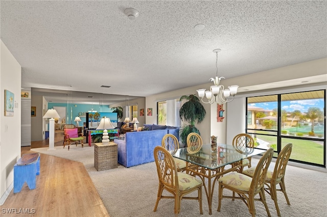 dining area featuring a textured ceiling, a notable chandelier, and carpet flooring