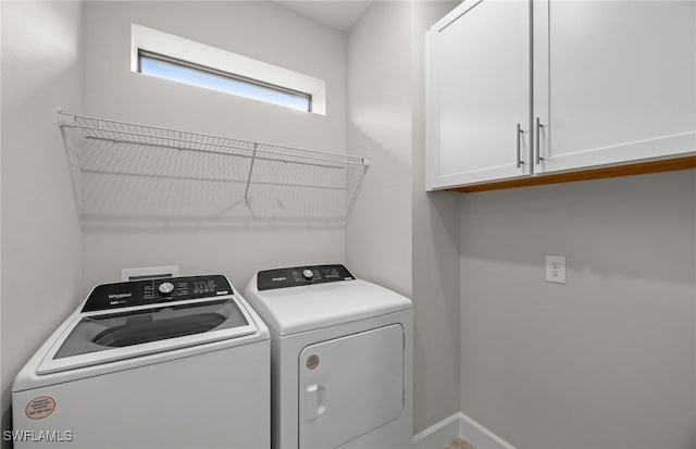 clothes washing area featuring cabinets and washer and clothes dryer