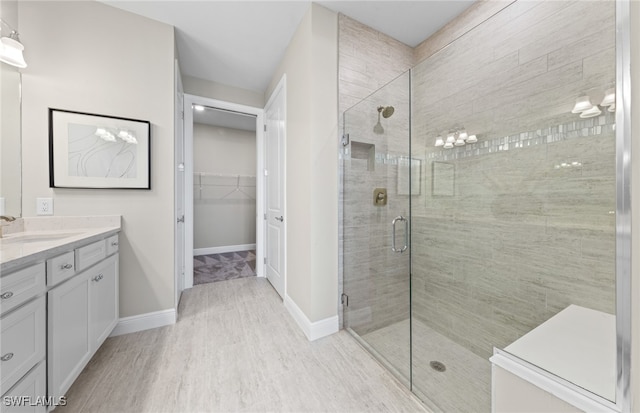 bathroom with hardwood / wood-style floors, a shower with shower door, and vanity