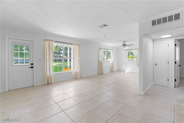 tiled spare room with ornamental molding, a textured ceiling, and ceiling fan