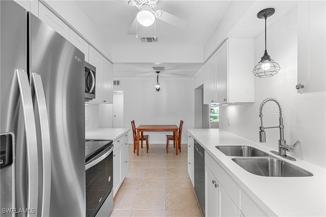 kitchen with stainless steel appliances, decorative light fixtures, light tile patterned floors, sink, and white cabinets