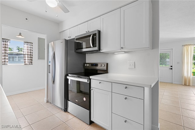 kitchen featuring stainless steel appliances, light tile patterned flooring, white cabinets, and a healthy amount of sunlight