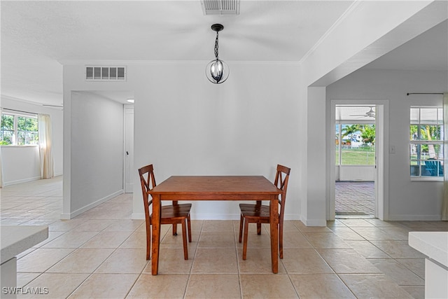 tiled dining space featuring crown molding and plenty of natural light