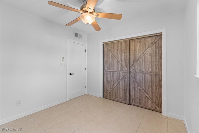 unfurnished bedroom with light tile patterned flooring, ceiling fan, and a closet