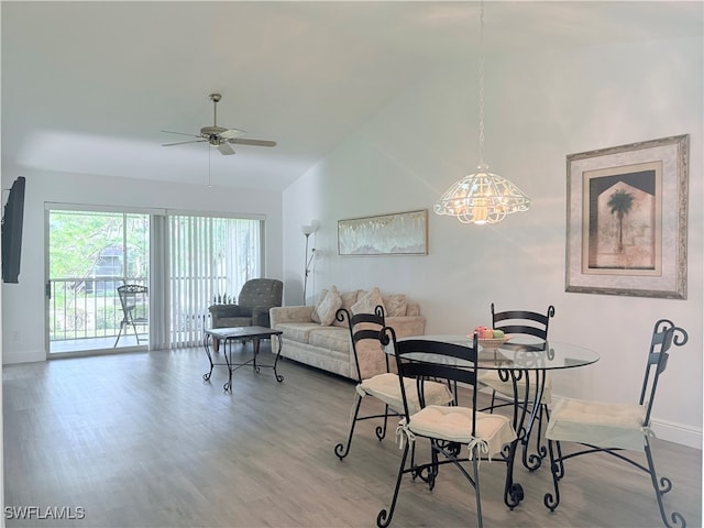 dining room featuring wood-type flooring, ceiling fan with notable chandelier, and vaulted ceiling