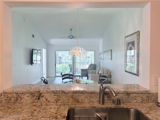 kitchen featuring light stone counters, sink, ceiling fan, and vaulted ceiling