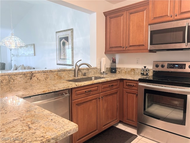 kitchen with hanging light fixtures, sink, light tile patterned floors, light stone countertops, and appliances with stainless steel finishes