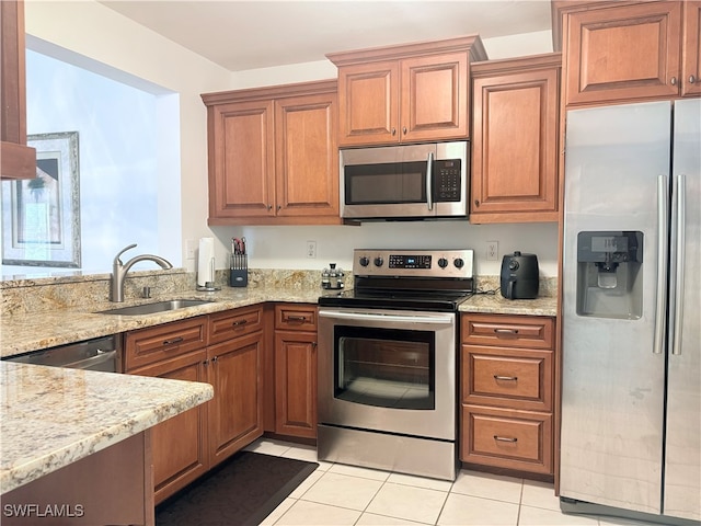 kitchen with light stone countertops, appliances with stainless steel finishes, sink, and light tile patterned floors