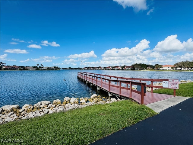 dock area with a water view and a lawn