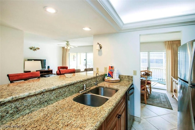 kitchen with light stone countertops, stainless steel fridge, sink, and a healthy amount of sunlight