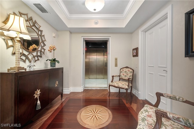 living area featuring dark hardwood / wood-style flooring, elevator, ornamental molding, and a raised ceiling