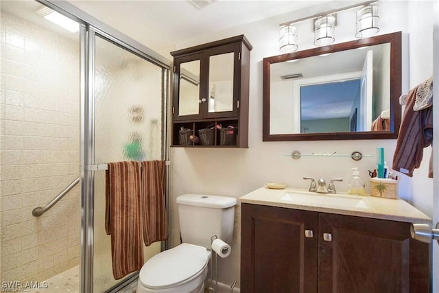 bathroom with toilet, vanity, and a shower with door