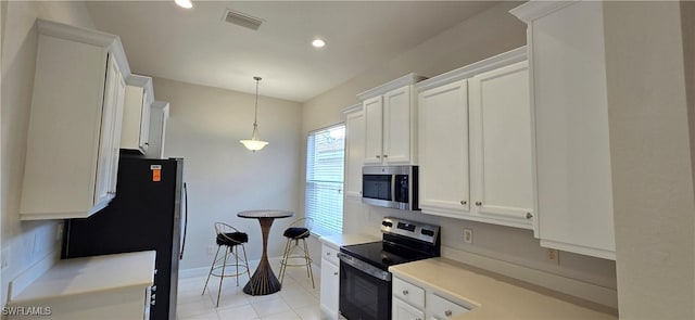 kitchen with stainless steel appliances, light tile patterned flooring, white cabinets, and decorative light fixtures